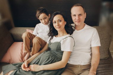 İki çocuklu bir aile kanepede oturuyor. Hafta sonu evde. Birlikte vakit geçirmek. Evde sevgi ve huzur