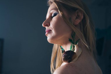 Manken salyangozu elinde tutuyor. Kozmetik, anti-yerçekimi kremleri, dudak tedavisi, yüz bakımı, botaks, gençleştirme, sağlıklı beslenme, kırışıklıklar ve kırışıklıklar için reklamlar. Fransız mutfağı kavramı