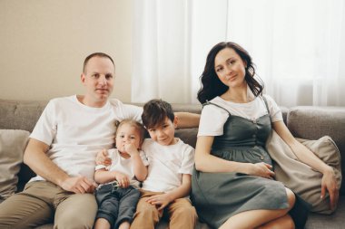 İki çocuklu bir aile kanepede oturuyor. Hafta sonu evde. Birlikte vakit geçirmek. Evde sevgi ve huzur