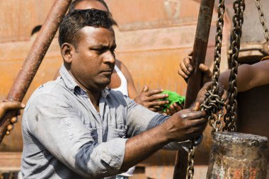 Dhaka, Bangladesh, 24 Şubat 2017: Dhaka Bangladeş, yağ bulaşmış kendi elleriyle tersanesinde çalışan bir gemi sürücü aks dolanmış bir zincir takmak.