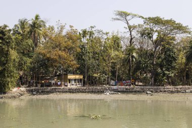 Yatay, tropikal bitki örtüsüne ve Bangladeş'te bir Riverside'da evleri