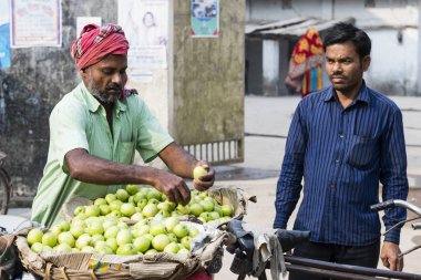 Burimari, Bangladesh, March 3 2017: Hawker with his bike sells apples to a local clipart