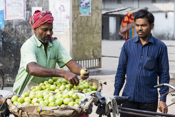 Burimari, Bangladesh, March 3 2017: Hawker with his bike sells apples to a local