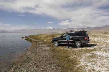 Karakul, Tacikistan, 22 Ağustos 2018: Araba sürücüsü Tacikistan pamir dağlarında Karakul town yakınındaki Karakul Gölü ile