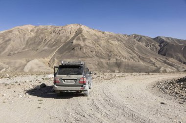 Langar, Tacikistan, 23 Ağustos 2018: Off-road araç Pamir Nehri üzerinde Pamir karayolu üzerinde bekliyor. Arka planda Afganistan dağlarında vardır