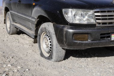 Langar, Tajikistan, August 23 2018: Flat tire on the Pamir Highway near Langar in the border area between Tajikistan and Afghanistan clipart