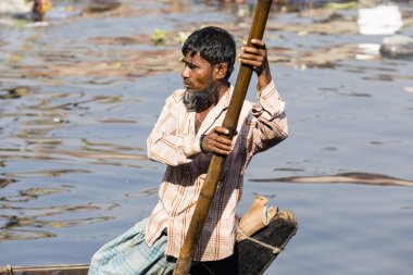 Dakka, Bangladeş, 24 Şubat 2017: Dhaka Bangladeş'te Buriganga Nehri'nin iki nehir arasındaki feribot görür onun eski ahşap tekne bir kürekçi portresi
