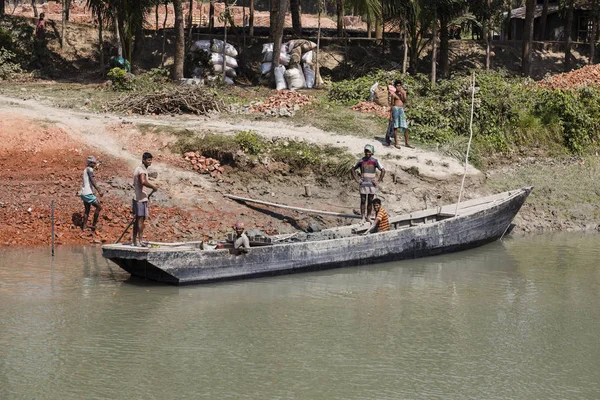 Morrelganj, Bangladesh, 27 de febrero de 2017: A orillas del río en Bangladesh, se están descargando ladrillos de un viejo barco de madera — Foto de Stock