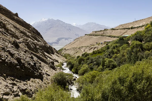 Valle lateral con arroyo cerca de Vrang con montañas Pamir en Tayikistán. Las montañas en el fondo son el Hindu Kush en Afganistán — Foto de Stock