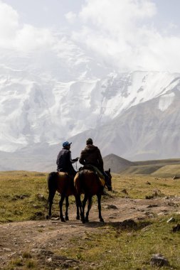 Tulpar, Kırgızistan 21 Ağustos 2018: İki Kırgız biniciler atlarını Merkez kampına Peak Lenin Kırgızistan'ın eteklerinde binmek.
