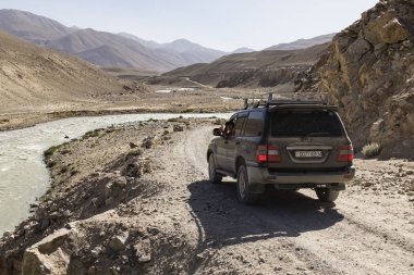 Langar, Tacikistan, 23 Ağustos 2018: Off-road araç Pamir Nehri üzerinde Pamir karayolu üzerinde bekliyor. Nehrin sol tarafta Afganistan olduğunu ve doğru Tacikistan