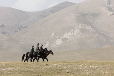 Şarkı Kul, Kırgızistan, 8 Ağustos 2018: Üç Kırgız insanlarla atlarını bozkır şarkı Kul Gölü Kırgızistan'yoluyla yolculuk