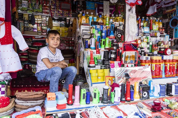 Khorog, Tajiquistão 25 de agosto de 2018: Bonito menino está sentado em sua tenda, esperando o comprador de suas mercadorias, Khorog, Tajiquistão — Fotografia de Stock