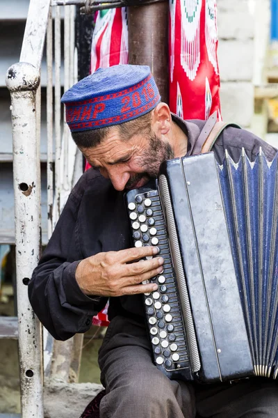 Khorog, Tádžikistán, 20 srpen 2018: Starý hudebník hraje na bazaru v Khorog na jeho akordeon — Stock fotografie