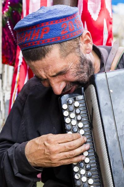 Khorog, Tayikistán, 20 de agosto de 2018: Un viejo músico toca en el bazar en Khorog con su acordeón — Foto de Stock