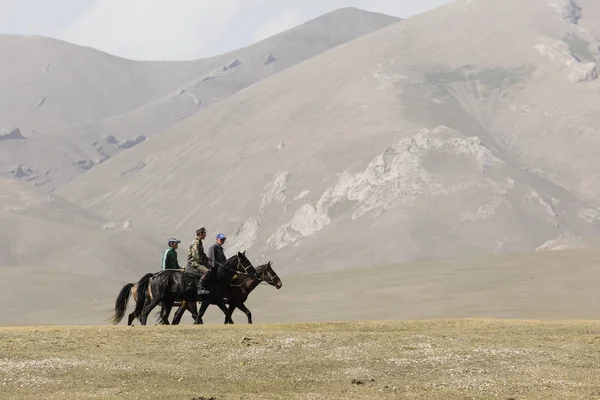 Song Kul, Kyrgyzstán, 8 srpen 2018: Tři Kyrgyz lidi jezdit koně přes stepi u jezera Song Kul v Kyrgyzstánu — Stock fotografie