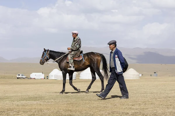 Song Kul, Kyrgyzstán, 8 srpen 2018: Kyrgyzština A na koně a Kyrgyz chůzi na stepi u jezera Song Kul v Kyrgyzstánu — Stock fotografie