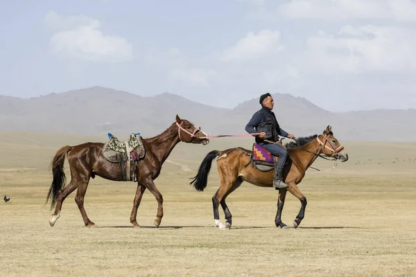 Song Kul, Kyrgyzstán, 8 srpen 2018: Kyrgyzština A jezdí koně a vede další na vodítku u jezera Song Kul v Kyrgyzstánu — Stock fotografie