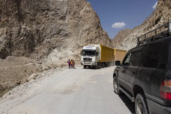 Khorog, Tayikistán 24 de agosto de 2018: Automóvil todoterreno y camión en la autopista Pamir en un cañón en el valle de Wakhan en Tayikistán (Afganistán en el lado izquierdo) ) — Foto de Stock