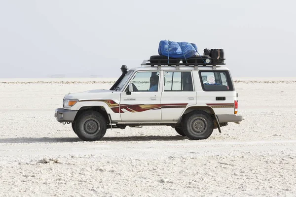 Danakil, Etiópia, 22 de fevereiro de 2015: um veículo off-road com seu motorista aguarda turistas no deserto salgado de Danakil — Fotografia de Stock