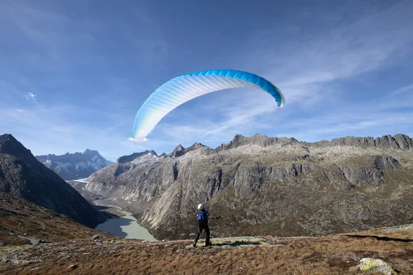 Piloto de parapente se para en una roca y equilibra su parapente por encima de su cabeza cerca del lago Grimsel en los Alpes suizos —  Fotos de Stock