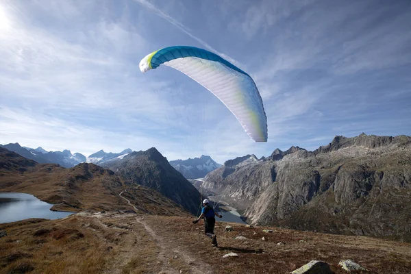 Пілот параплана знімає з його параплана, щоб зняти і летіти в долину в швейцарських Альпах. — стокове фото