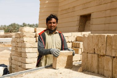 Raghba, Suudi Arabistan, 16 Şubat 2020: Suudi Arabistan 'da Müslüman bir inşaat işçisi bir kamyondan çamur tuğlaları boşaltıyor.