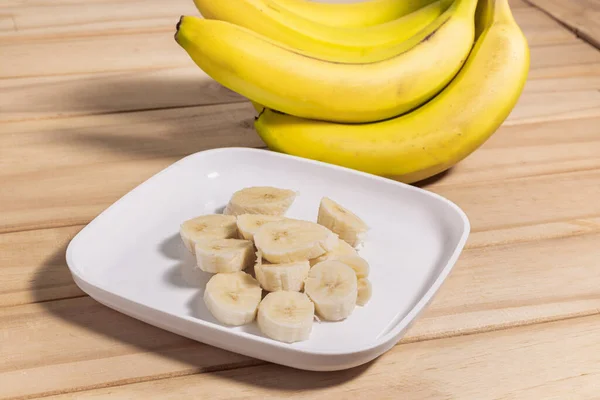 Bunch of bananas and sliced bananas on wooden table