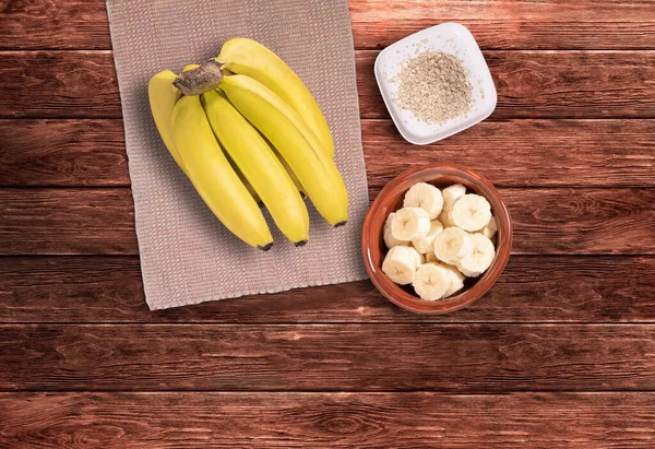 Bunch of bananas and sliced bananas on wooden table