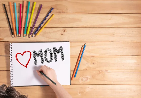 Kind Schreibt Love Mom Auf Weißem Laken Auf Holztisch — Stockfoto