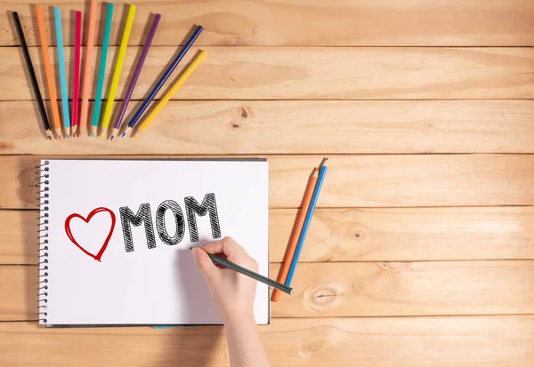 Kind Schreibt Love Mom Auf Weißem Laken Auf Holztisch — Stockfoto