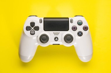 Sao Paulo, Brazil - 01/09/2020: White Playstation 4 controller on yellow background clipart