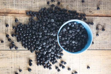 Dökülen beyaz kase dondurulmuş aronia çilek ahşap rustik masa üzerinde ile dolu