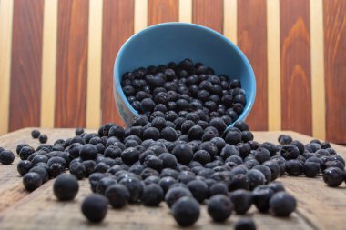 Dökülen beyaz kase dondurulmuş aronia çilek ahşap rustik masa üzerinde ile dolu