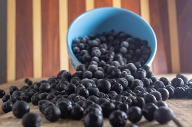 Dökülen beyaz kase dondurulmuş aronia çilek ahşap rustik masa üzerinde ile dolu