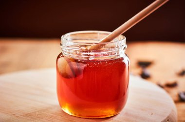 Cam kavanoz bal ile dolu. Tahta kaşık balla alarak