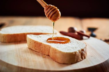 Tahta kaşıkla ekmek dilimleri üzerine yağan taze bal