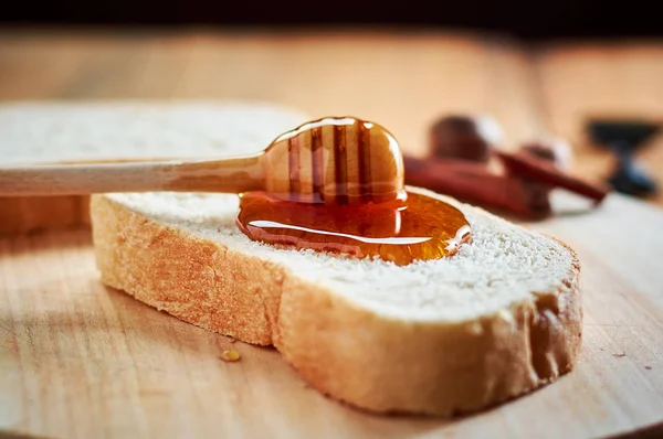 Pouring fresh honey on bread slices with wooden spoon