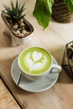 Yeşil çay matcha latte sanat ile ahşap masa üzerinde bir kahve dükkanı kafede bir açıyla kırpılmış etli 