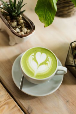 Yeşil çay matcha latte sanat ile ahşap masa üzerinde bir kahve dükkanı kafede bir açıyla kırpılmış etli 