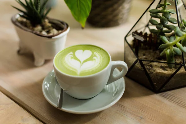 Yeşil çay matcha latte sanat ile ahşap masa üzerinde bir kahve dükkanı kafede bir açıyla kırpılmış etli 