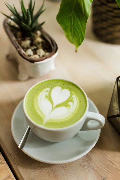 Yeşil çay matcha latte sanat ile ahşap masa üzerinde bir kahve dükkanı kafede bir açıyla kırpılmış etli 