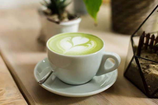 Yeşil çay matcha latte sanat ile ahşap masa üzerinde bir kahve dükkanı kafede bir açıyla kırpılmış etli 