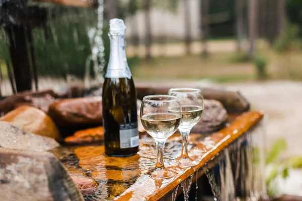 Aşk, romantizm, tatil, kutlama kavramı. Şişe ve bardak yaz orman şelale tarafından sunset Bulvarında soğutulmuş şampanya.