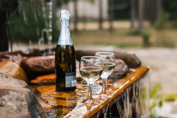 Aşk, romantizm, tatil, kutlama kavramı. Şişe ve bardak yaz orman şelale tarafından sunset Bulvarında soğutulmuş şampanya.