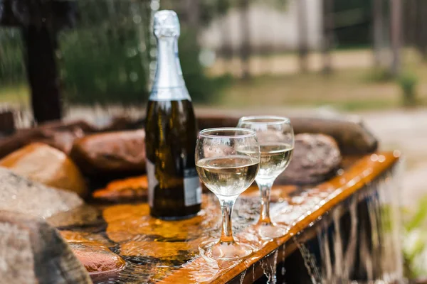 Aşk, romantizm, tatil, kutlama kavramı. Şişe ve bardak yaz orman şelale tarafından sunset Bulvarında soğutulmuş şampanya.