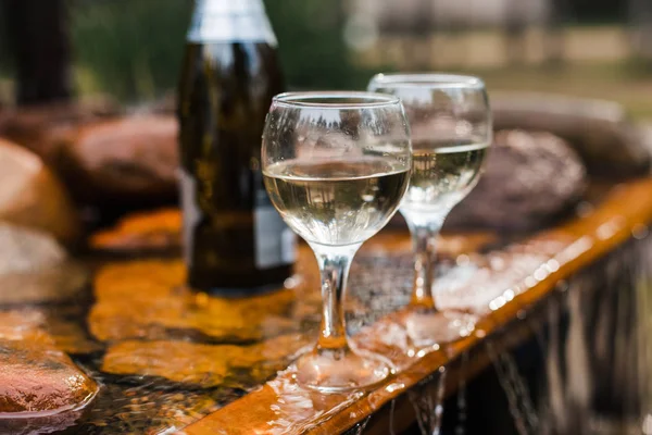 Aşk, romantizm, tatil, kutlama kavramı. Şişe ve bardak yaz orman şelale tarafından sunset Bulvarında soğutulmuş şampanya.