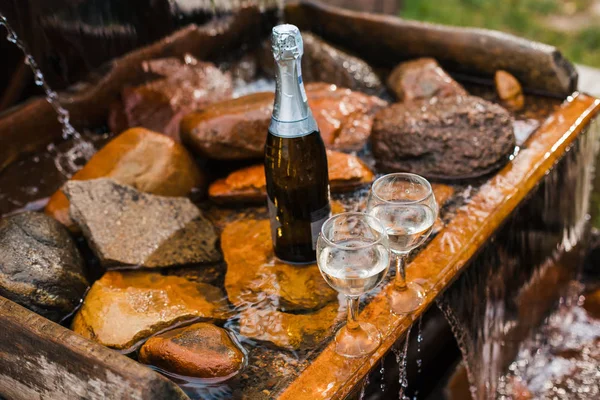 Aşk, romantizm, tatil, kutlama kavramı. Şişe ve bardak yaz orman şelale tarafından sunset Bulvarında soğutulmuş şampanya.