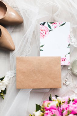 Davetiyeler düğün kağıtları masaya döşeme çiçekler, vual, yüksek topuklu ayakkabılar ve bir şişe tuvalet suyu ile süsleyin. Mockup boş kartpostal ile 