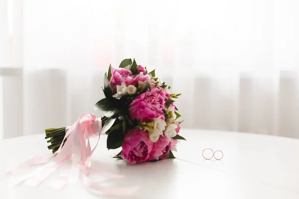 Güzel pembe peonies buket ve Alyans beyaz masaya yalan. Üstten görünüm. 